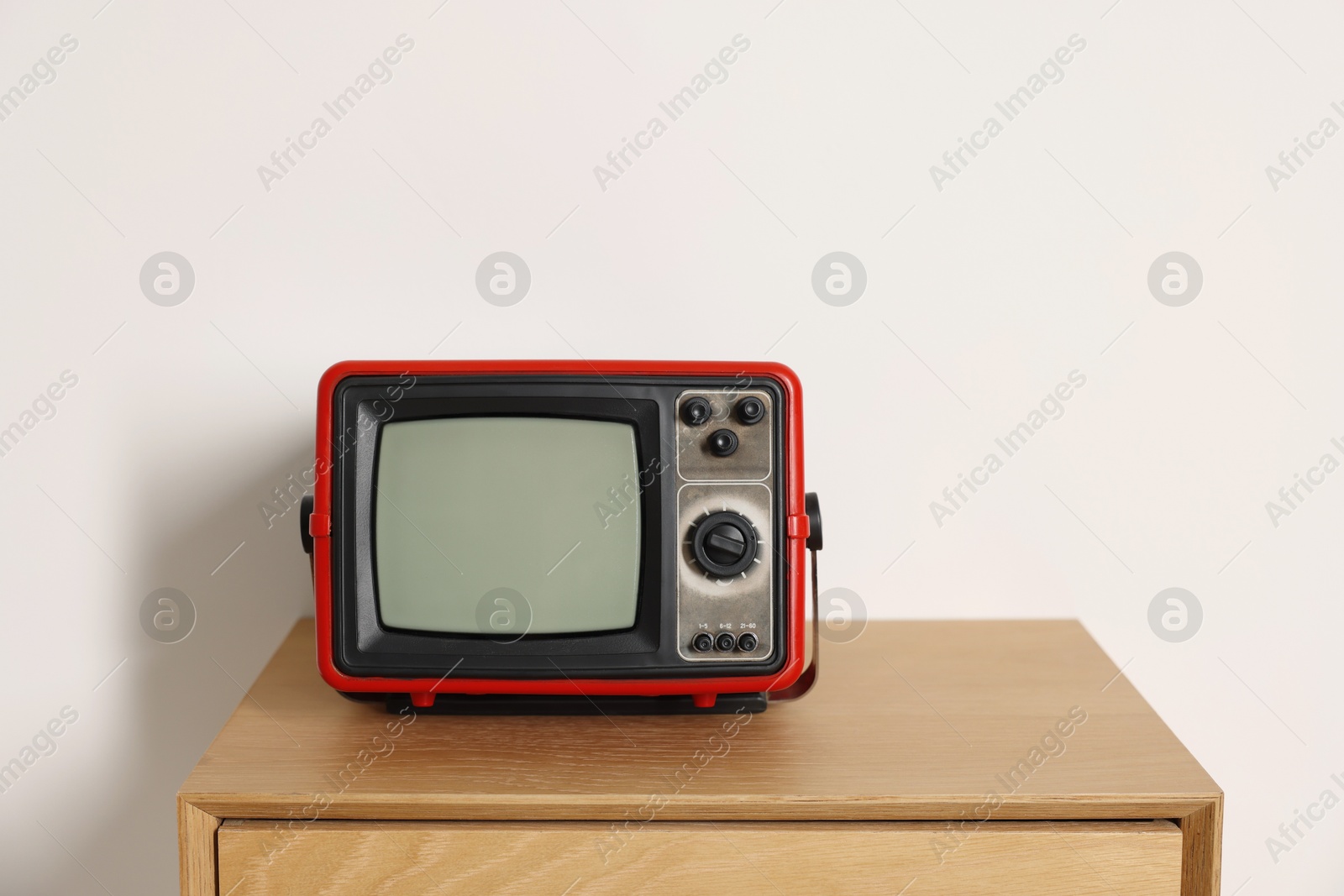 Photo of Retro tv set on nightstand against white wall