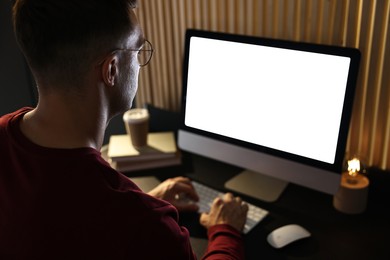 Photo of Man using computer monitor at table indoors