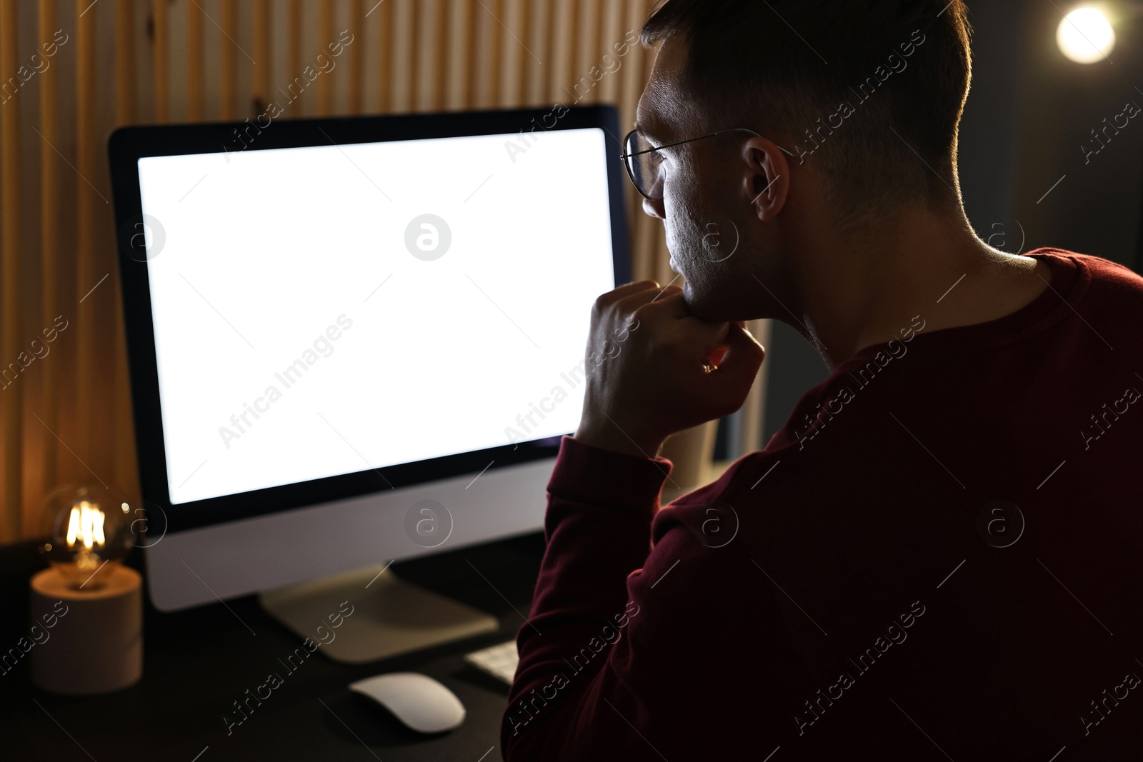 Photo of Man using computer monitor at table indoors