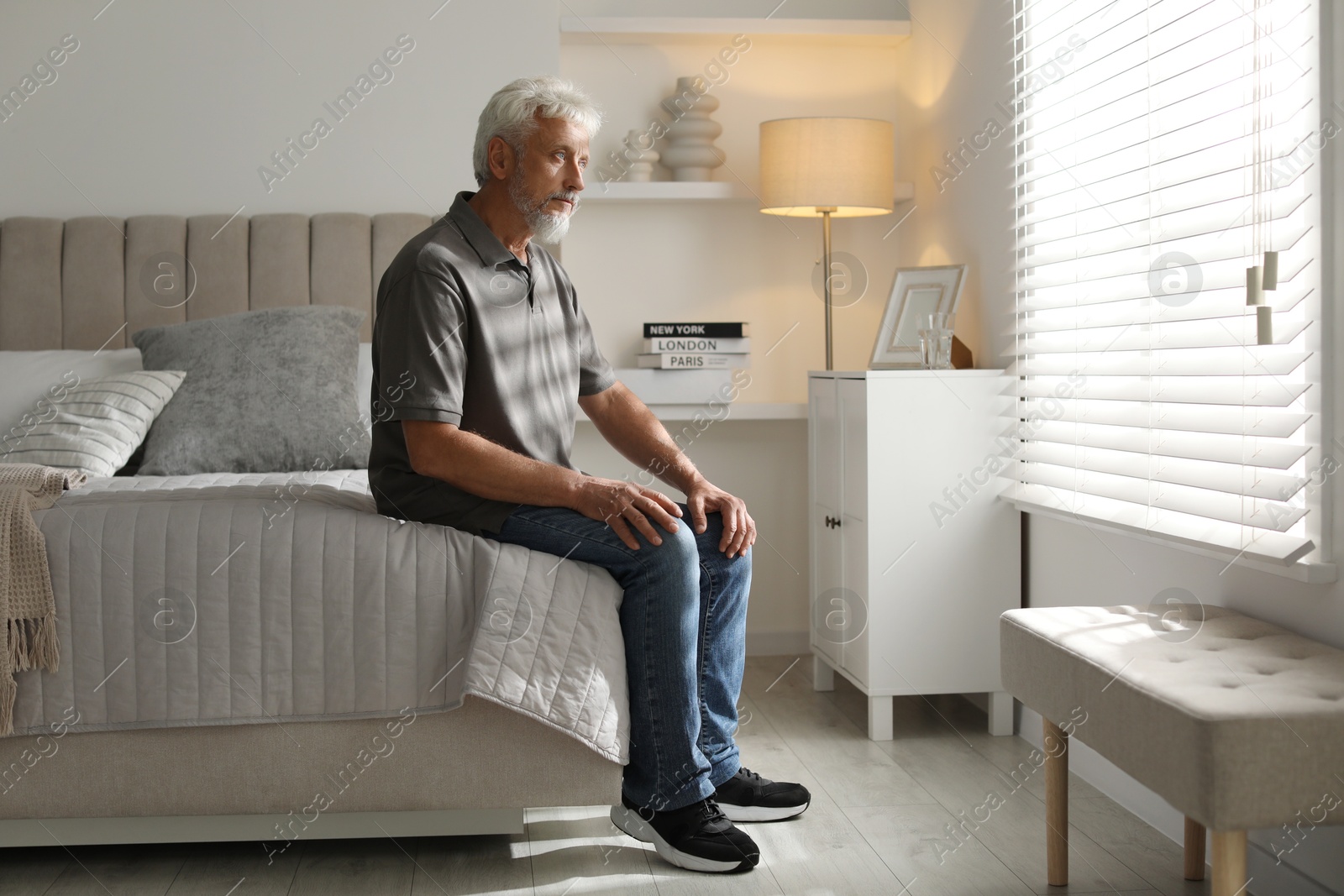 Photo of Lonely senior man sitting on bed at home