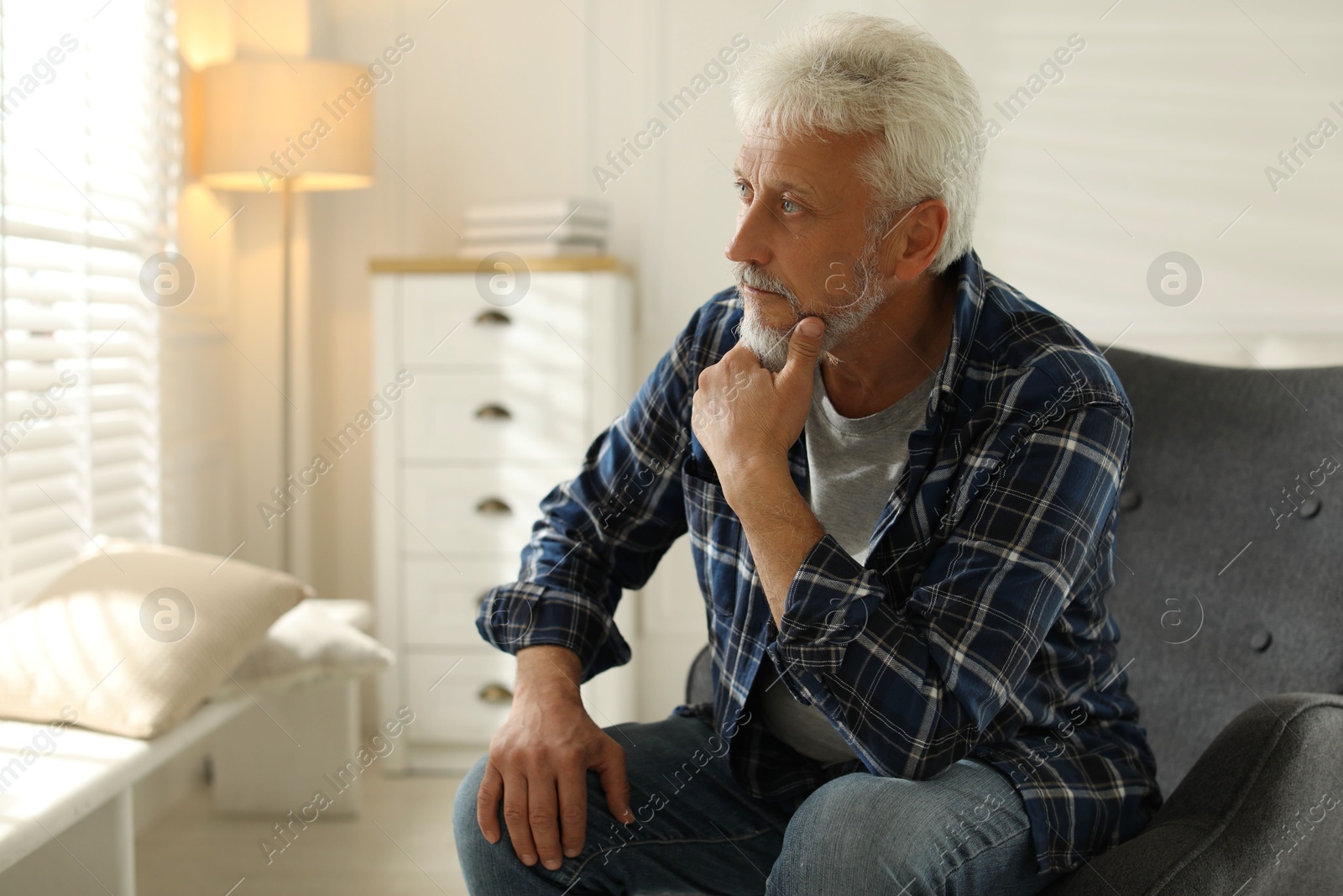 Photo of Lonely senior man sitting in armchair at home. Space for text