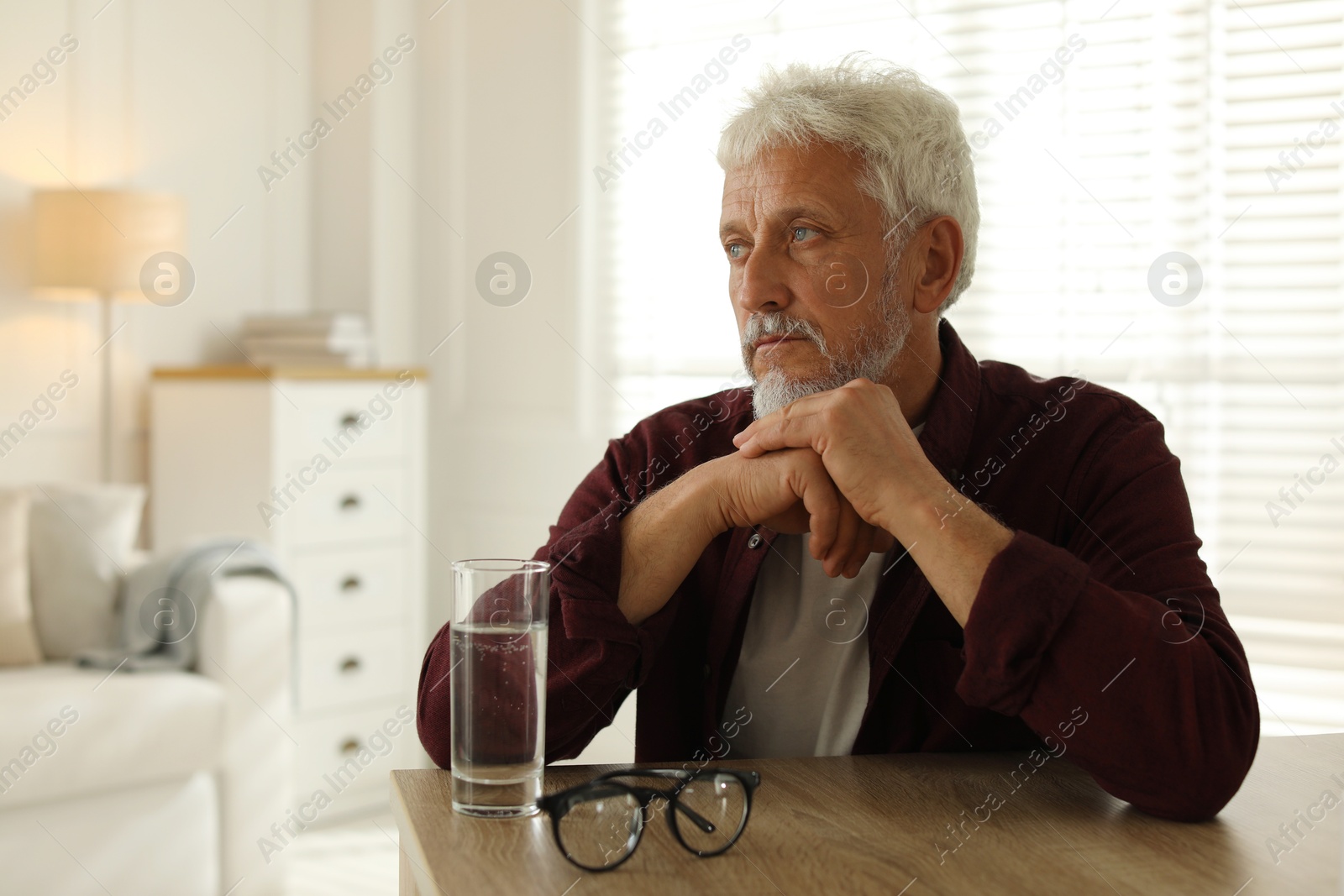 Photo of Sad senior man feeling lonely while sitting at wooden table indoors