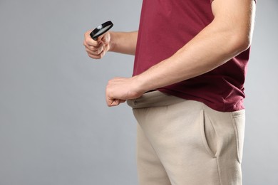 Photo of STD (sexually transmitted diseases). Man examining intimate area with magnifying glass on grey background, closeup