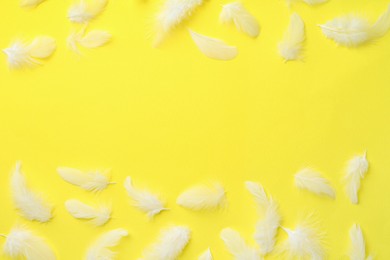 Photo of Beautiful fluffy feathers on yellow background, flat lay. Space for text