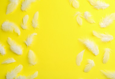 Photo of Beautiful fluffy feathers on yellow background, flat lay. Space for text