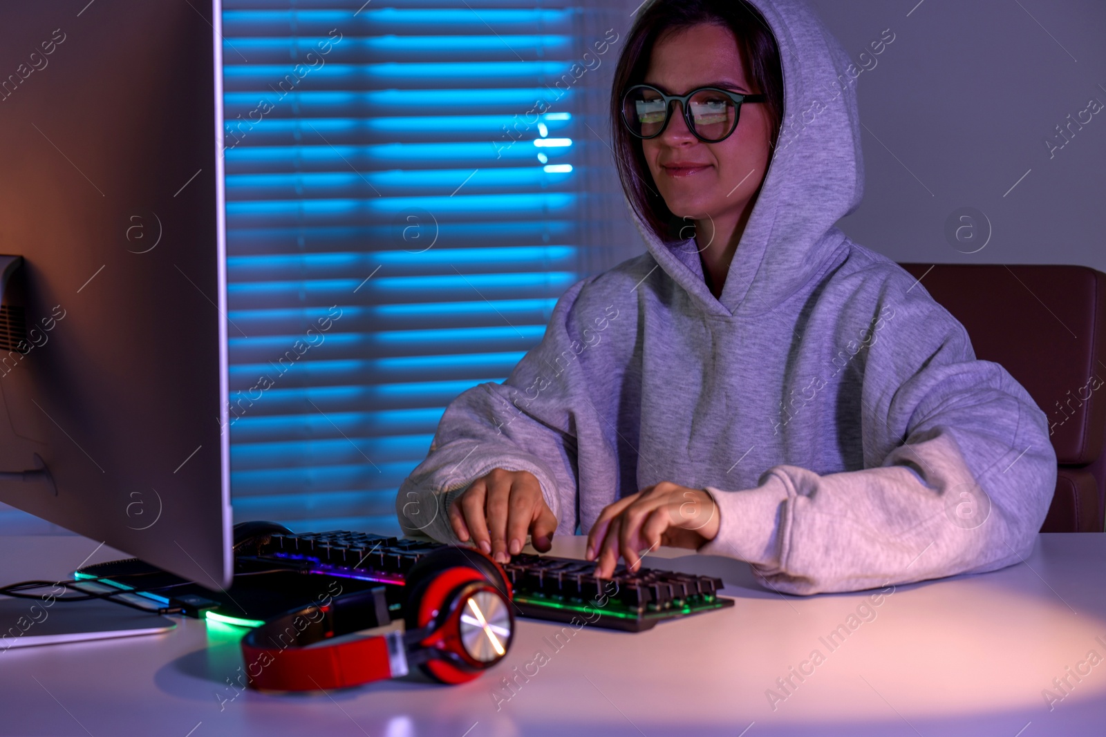 Photo of Woman playing video game with keyboard at table indoors