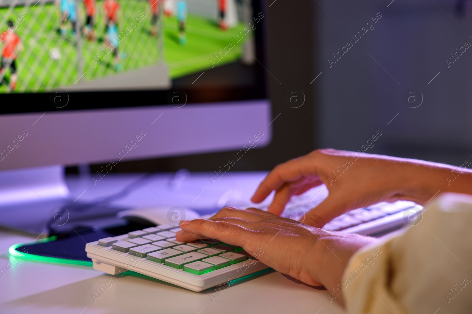 Photo of Woman playing video game with keyboard at white table indoors, closeup