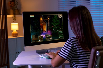 Photo of Woman playing video game with keyboard at table indoors, back view