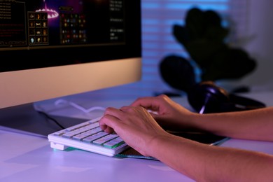 Photo of Woman playing video game with keyboard at white table indoors, closeup