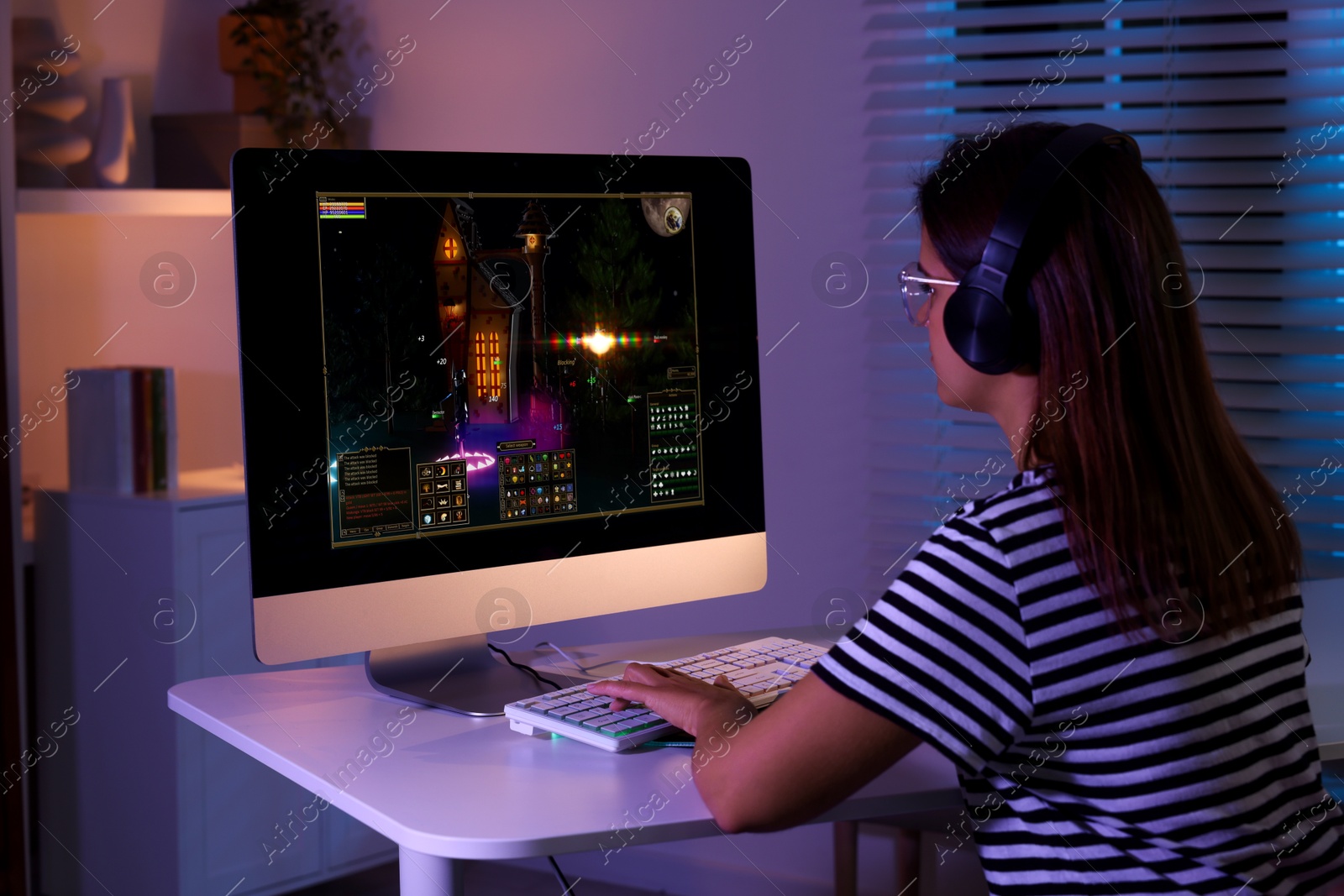 Photo of Woman playing video game with keyboard at table indoors