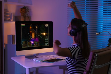 Photo of Woman playing video game with keyboard at table indoors