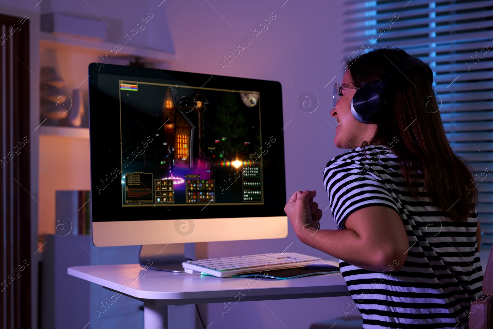 Photo of Woman playing video game with keyboard at table indoors