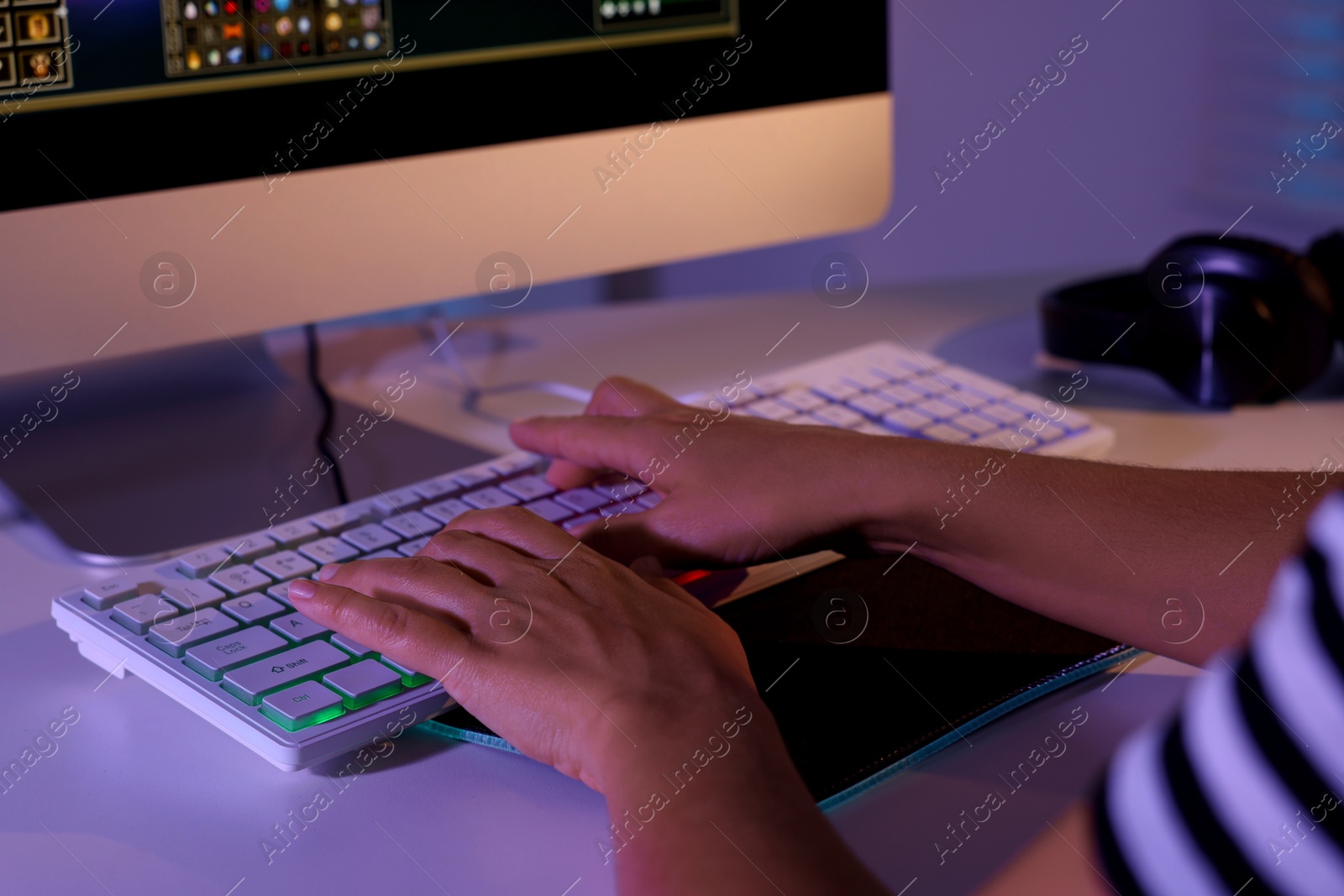 Photo of Woman using computer keyboard at white table indoors, closeup