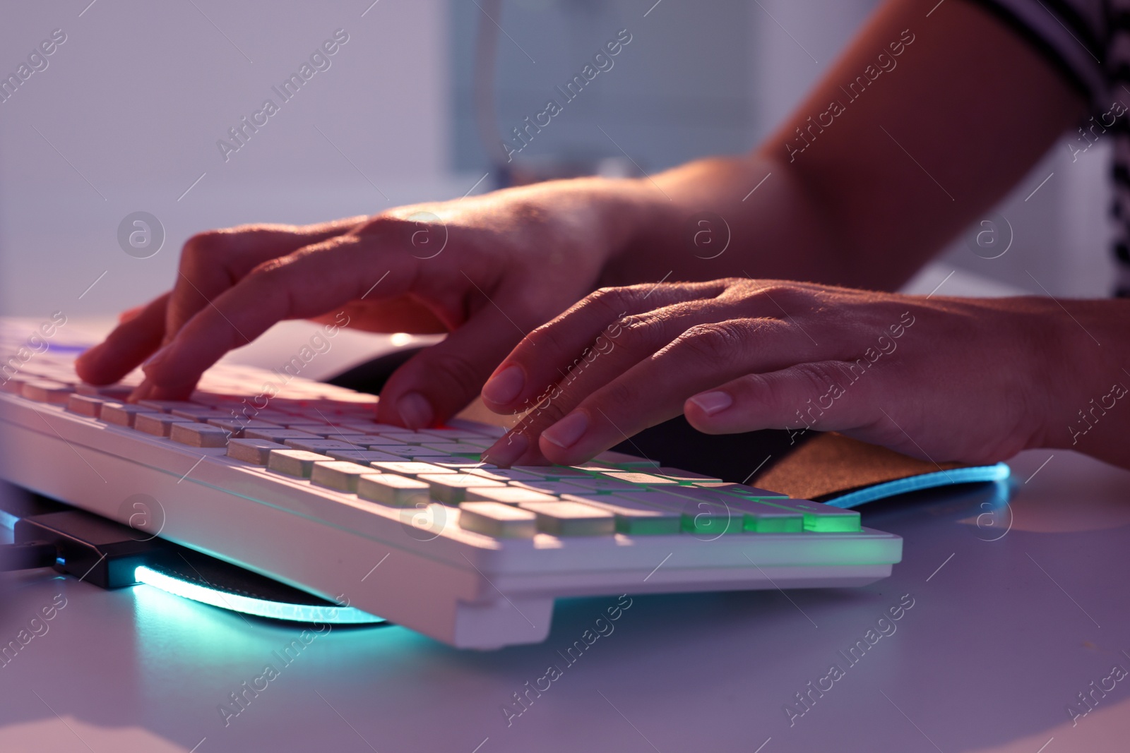 Photo of Woman using computer keyboard at white table indoors, closeup