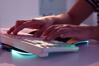 Photo of Woman using computer keyboard at white table indoors, closeup