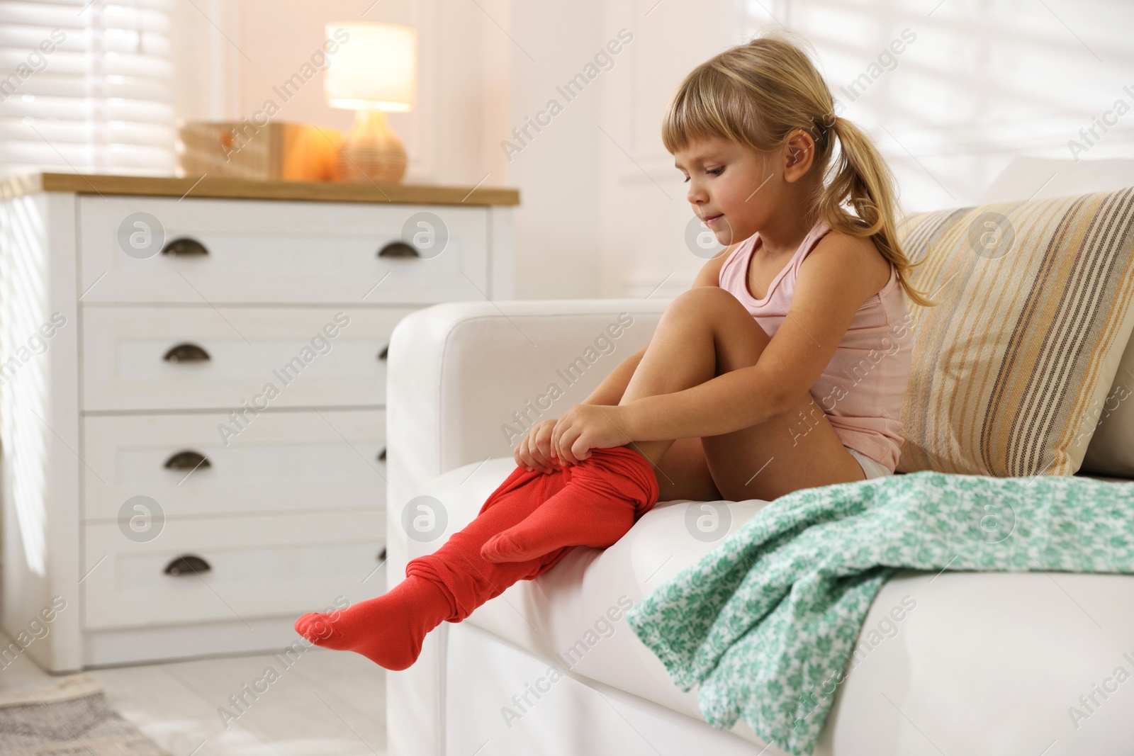 Photo of Little girl putting on soft tights at home. Space for text