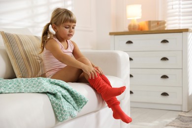 Photo of Little girl putting on soft tights at home. Space for text