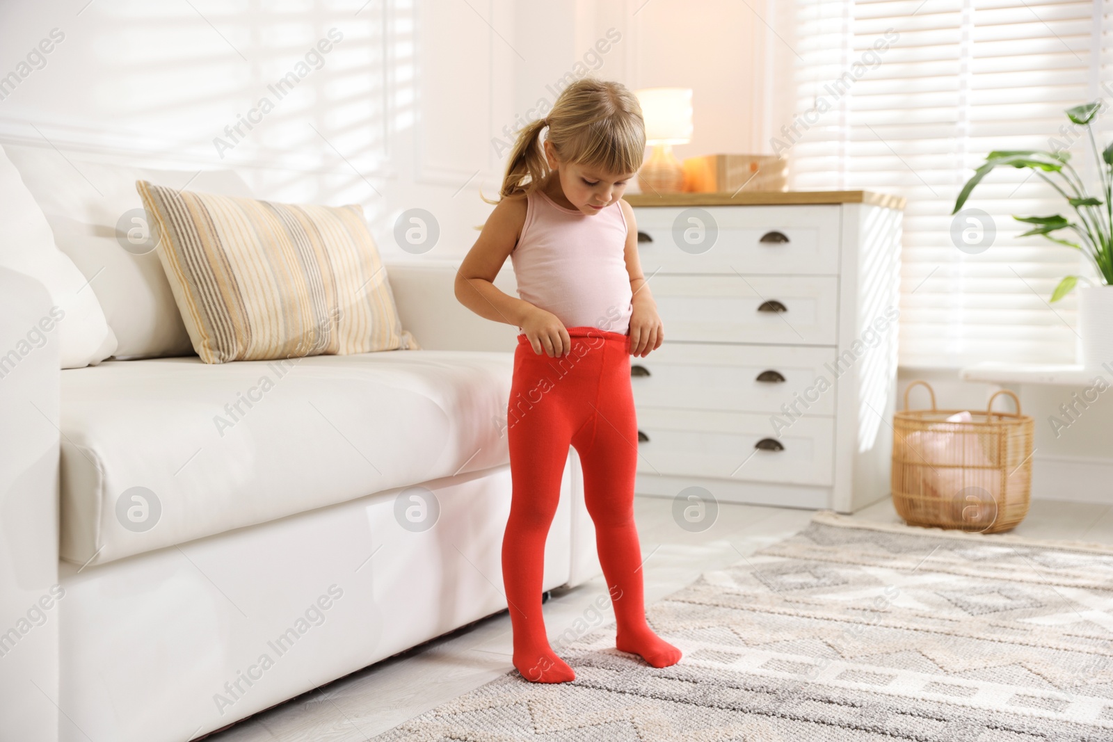 Photo of Little girl putting on soft tights at home