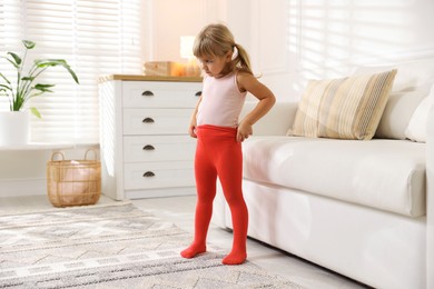 Photo of Little girl putting on soft tights at home