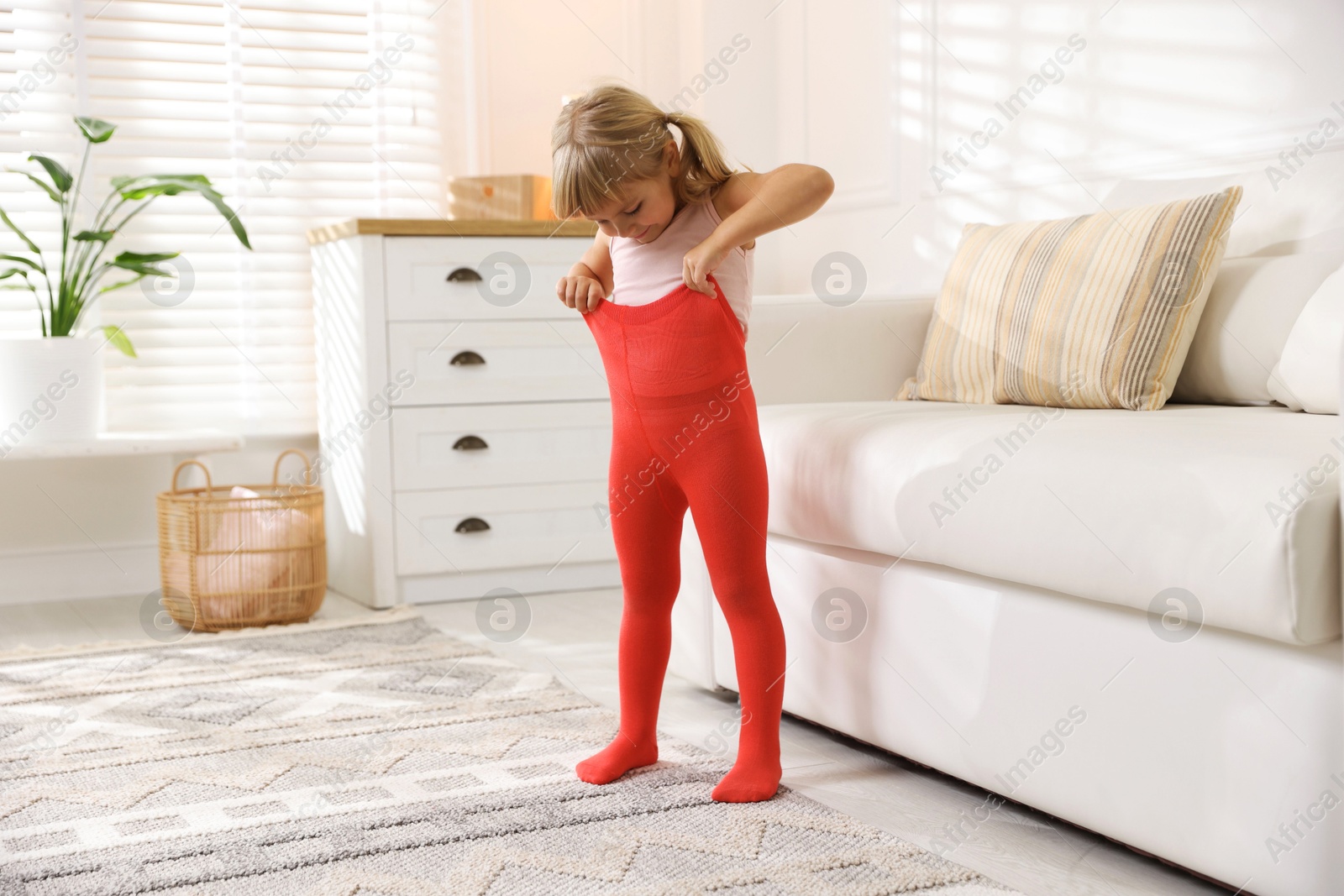 Photo of Little girl putting on soft tights at home