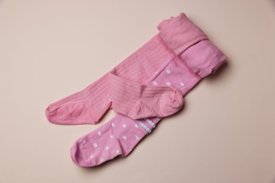 Photo of Beautiful pink child's tights on beige background, top view