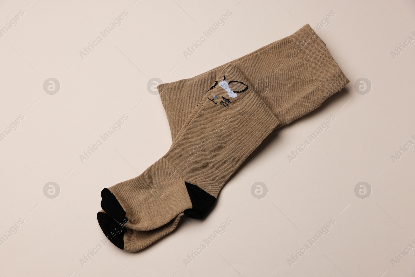 Photo of Beautiful brown child's tights on beige background, top view