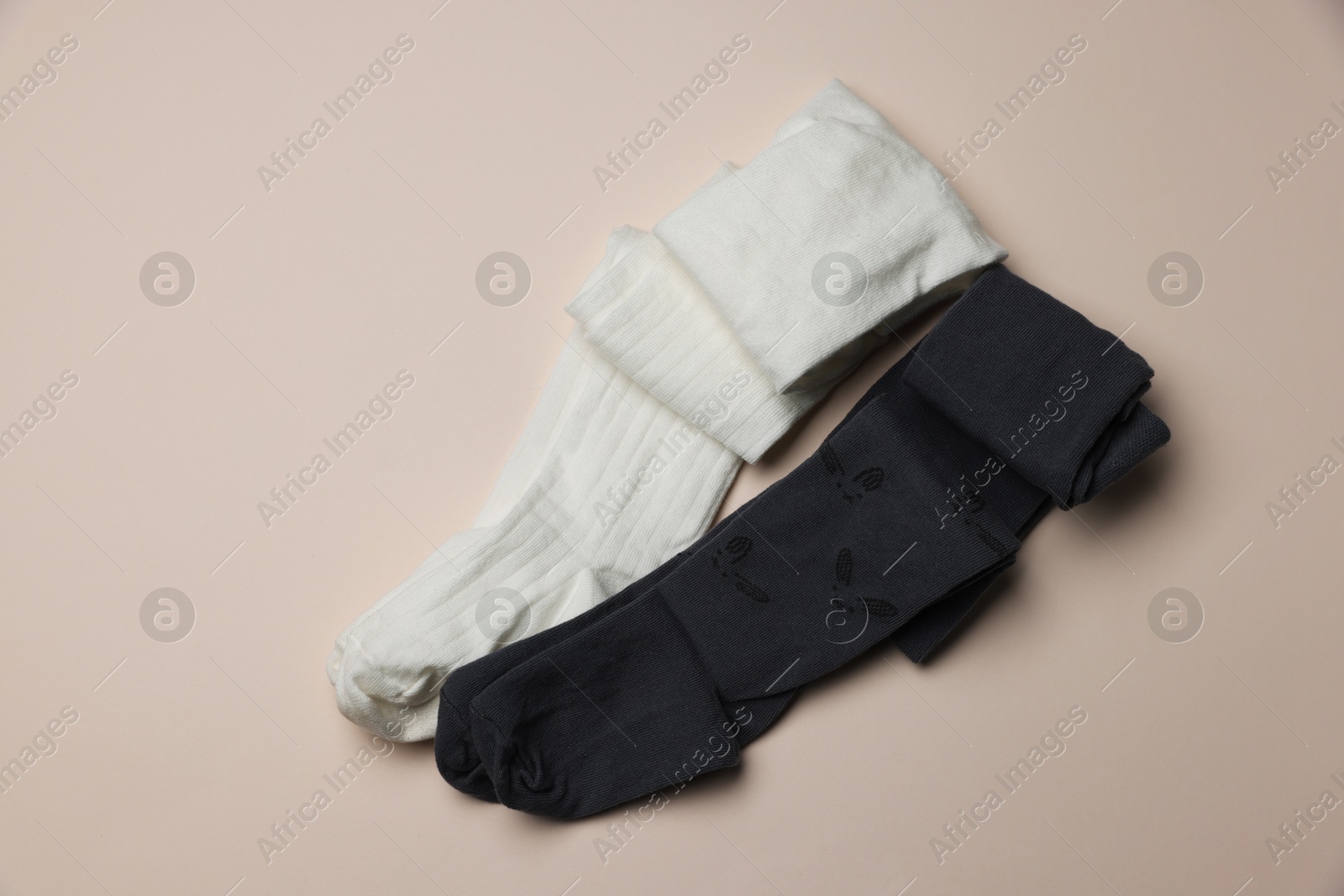 Photo of Different child's tights on beige background, top view