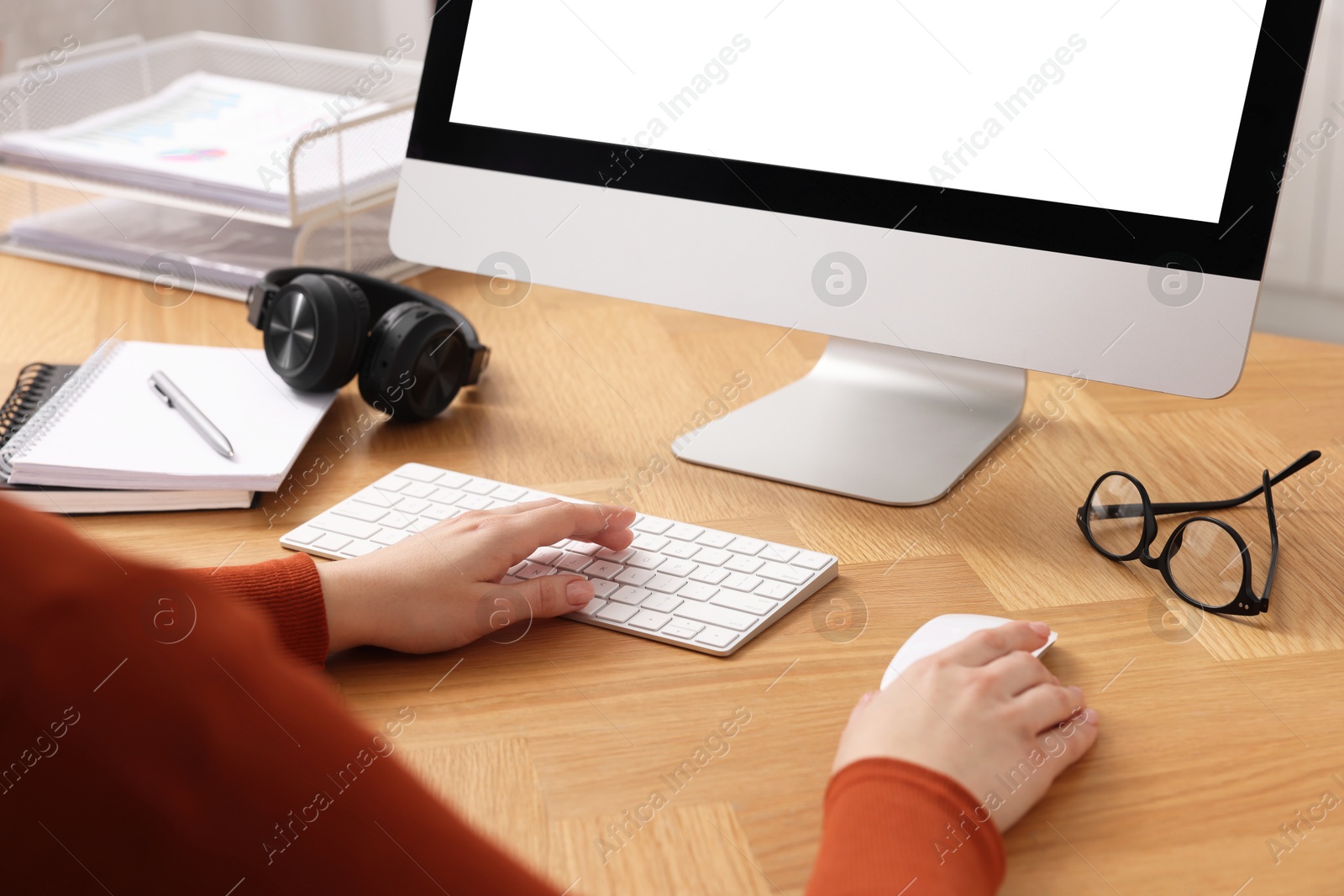 Photo of Woman working on computer at wooden table in office, closeup