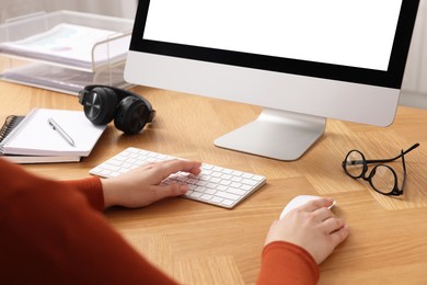 Photo of Woman working on computer at wooden table in office, closeup