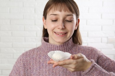 Photo of Smiling woman with tasty mochi near white wall