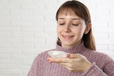 Photo of Smiling woman with tasty mochi near white wall. Space for text