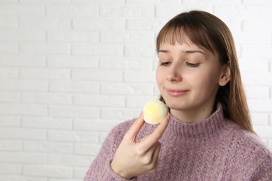 Photo of Beautiful woman with tasty mochi near white wall. Space for text