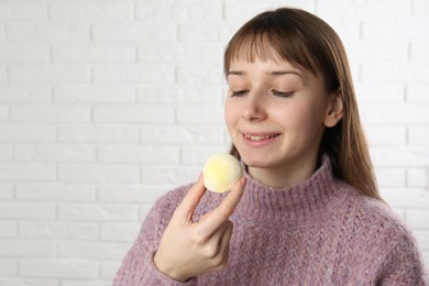 Photo of Smiling woman with tasty mochi near white wall. Space for text