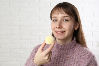 Photo of Smiling woman with tasty mochi near white wall. Space for text