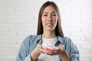 Photo of Smiling woman with tasty mochi near white wall