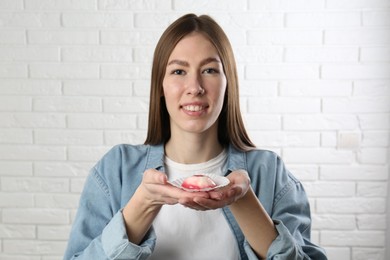 Photo of Smiling woman with tasty mochi near white wall