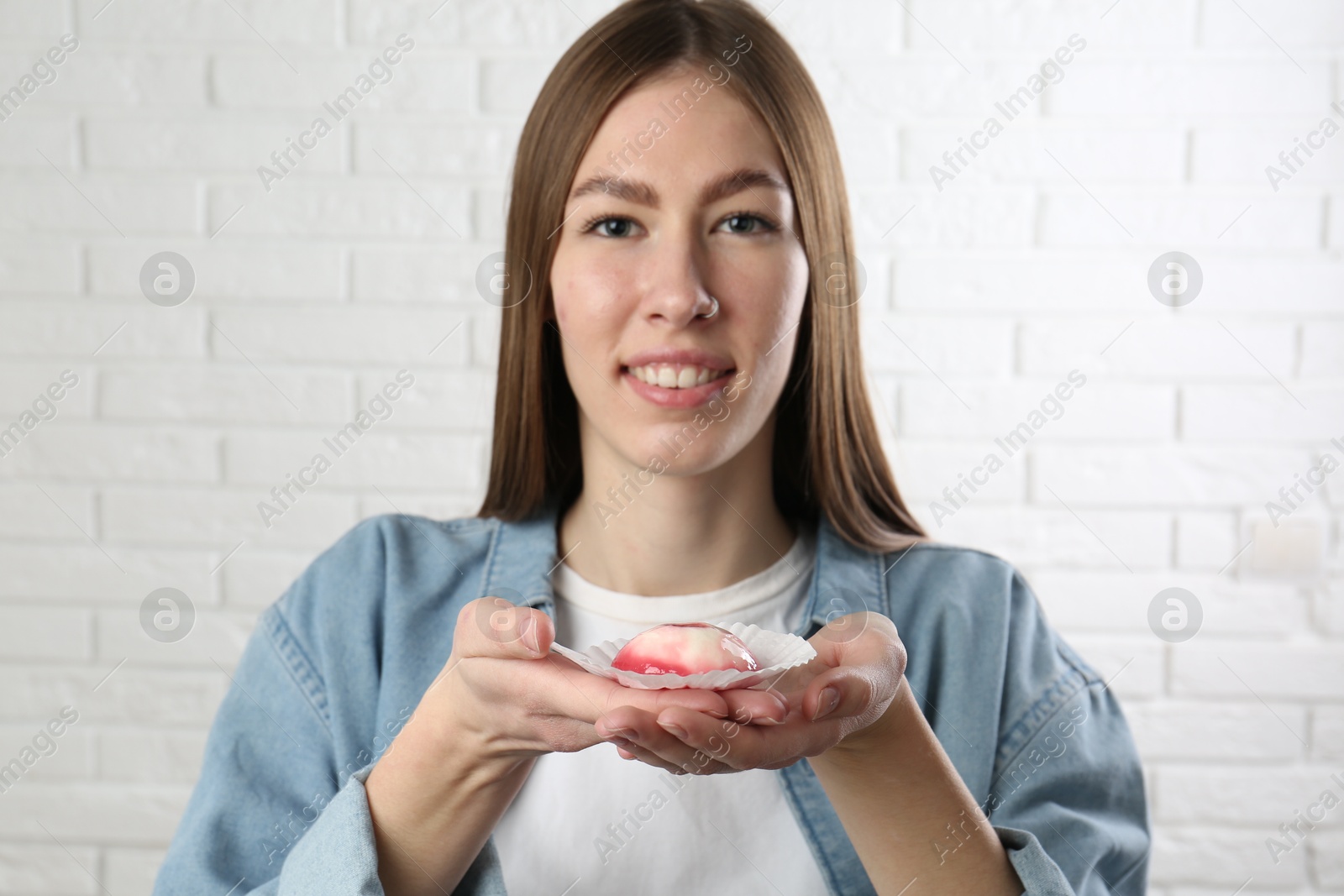 Photo of Smiling woman with tasty mochi near white wall