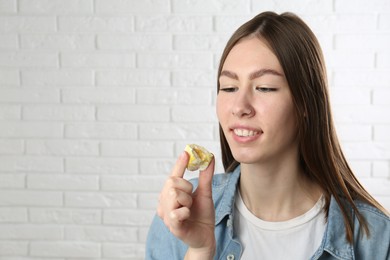 Photo of Smiling woman with tasty mochi near white wall. Space for text