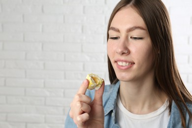 Photo of Smiling woman with tasty mochi near white wall. Space for text