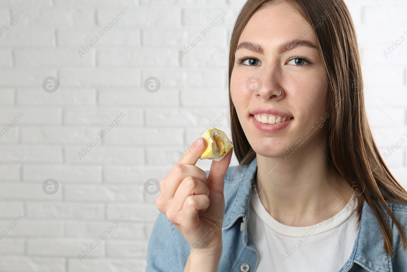 Photo of Smiling woman with tasty mochi near white wall. Space for text