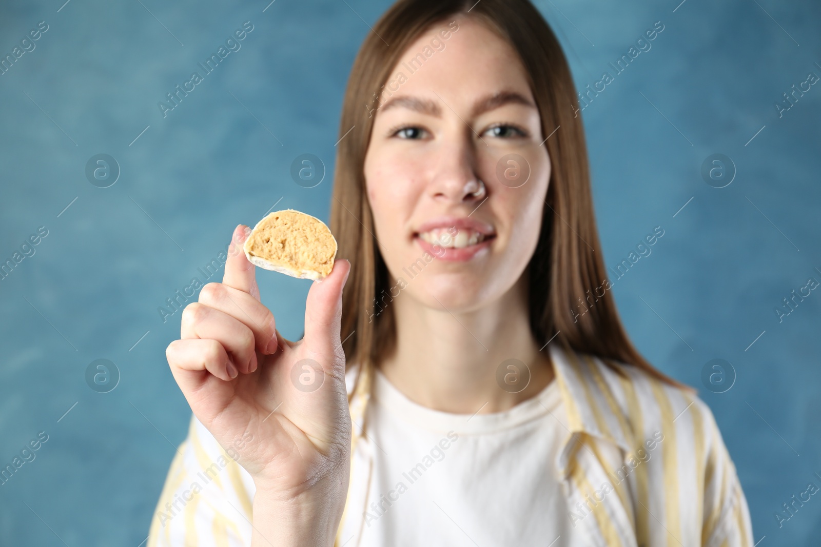 Photo of Smiling woman with tasty mochi on blurred blue background, selective focus