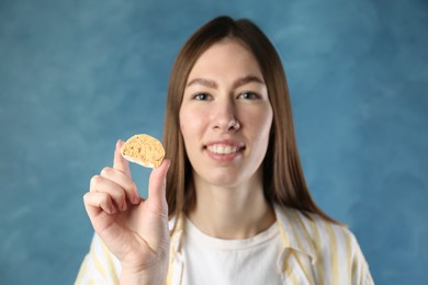 Smiling woman with tasty mochi on blurred blue background, selective focus