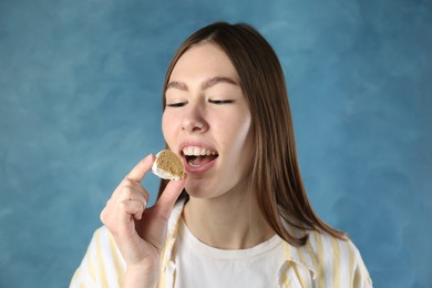 Photo of Beautiful woman eating tasty mochi on blurred blue background