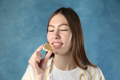 Photo of Beautiful woman eating tasty mochi on blurred blue background