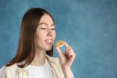 Photo of Beautiful woman eating tasty mochi on blurred blue background. Space for text