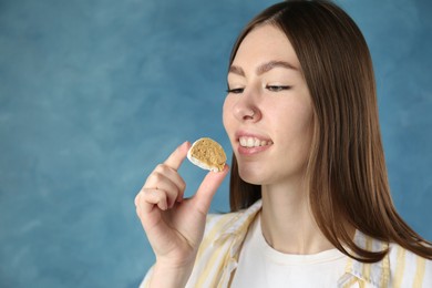 Photo of Beautiful woman eating tasty mochi on blurred blue background. Space for text