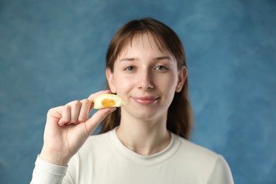 Photo of Beautiful woman with tasty mochi on blurred blue background, selective focus