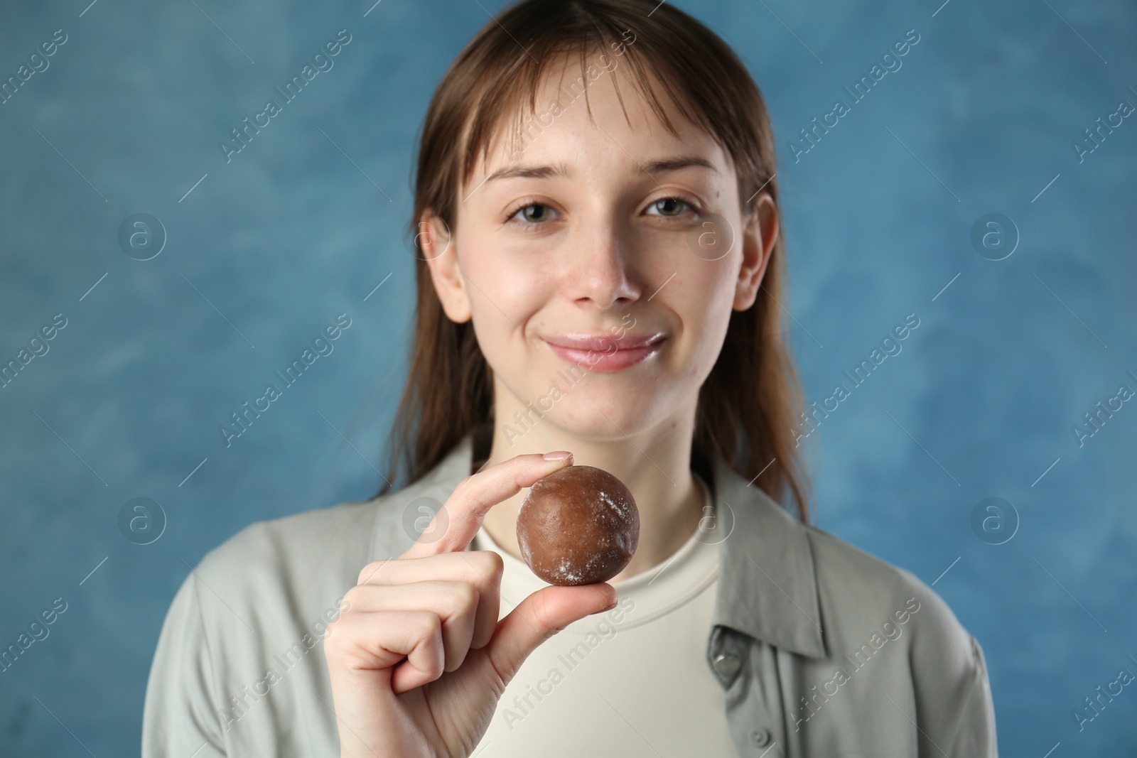 Photo of Beautiful woman with tasty mochi on blurred blue background