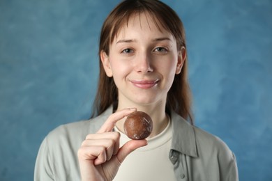 Photo of Beautiful woman with tasty mochi on blurred blue background