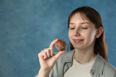 Photo of Smiling woman with tasty mochi on blurred blue background. Space for text